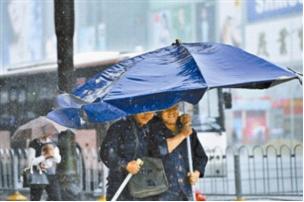 两名工人撑着巨大的雨伞（雨伞边上有反光材料应该更安全）走在暴雨中。 